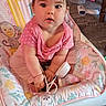 baby, child, infant, pink_clothing, baby_chair, floral_pattern, indoor, cute, curious, face, human, seat, toy, person, sitting, young_child, plush, home_interior, floor, furniture