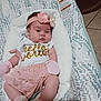 baby, infant, headband, flower, shirt, text, pink, white, cushion, seat, pattern, floor, tile, clothing, socks, newborn, resting, indoors, person, cute