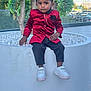 boy, bracelet, cars, child, daylight, earring, fashion, glass_barrier, outdoor, pants, plant, planter, portrait, red_jacket, sidewalk, sitting, tree, urban, white_shoes, white_stones