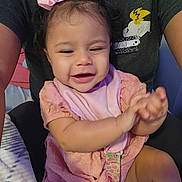 Aurora joined the competition — help win amazing prizes! baby, child, infant, smiling, happy, portrait, pink_bow, pink_clothing, bib, sitting, hands, face, dark_hair, indoor, adult, caregiver, car_seat, closeup, cute, photograph