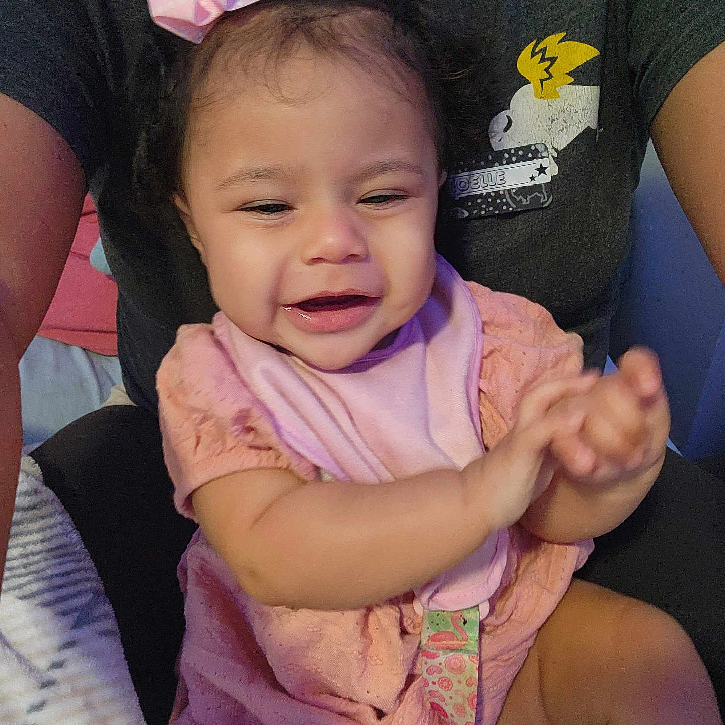Aurora joined the competition — help win amazing prizes! baby, child, infant, smiling, happy, portrait, pink_bow, pink_clothing, bib, sitting, hands, face, dark_hair, indoor, adult, caregiver, car_seat, closeup, cute, photograph