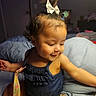 Aurora joined the competition — help win amazing prizes! child, toddler, baby, girl, portrait, sitting, bedroom, bed, blanket, pillow, denim, romper, hair_bow, smiling, curious, indoor, close_up, arm, toy, home