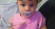 Aurora joined the competition — help win amazing prizes! baby, infant, child, portrait, sitting, pink_clothing, headband, bow, pacifier, pacifier_clip, wide_eyes, curly_hair, indoors, couch, blanket, close_up, front_facing, cute, baby_clothing, hand