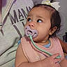 Aurora is registered to the contest to win money with this photo: baby, child, infant, portrait, pacifier, bow, hair, smiling, curious, sitting, indoor, clothing, bib, strap, hand, arm, face, eyes, couch, close_up