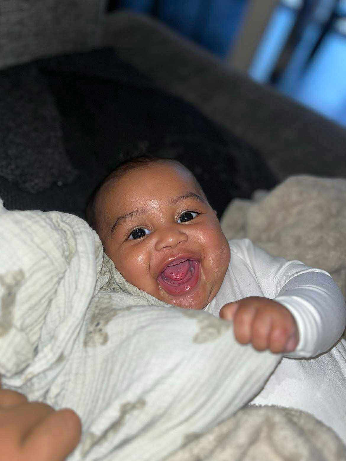 Alioune Tikilagi a rejoint le concours — aidez-le/la à gagner de superbes lots ! baby, smiling, happy, face, blanket, infant, close_up, cute, child, warm, soft, indoor, comfort, joy, person, clothing, hand, portrait, young, expression