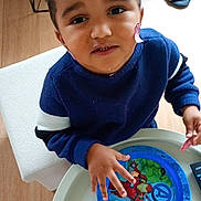 Zayn participe au concours pour gagner de l'argent avec cette photo : avengers, blue_sweater, child, curly_hair, cute, face, food, hand, indoor, person, plate, playful, room, slippers, smiling, table, toddler, toy, wood_floor, young