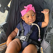 Alana is registered to the contest to win money with this photo: baby, child, stroller, headband, pink, pacifier, clip, black, clothing, seatbelt, infant, cute, person, sitting, outdoor, safety, expression, looking, toddler, portrait