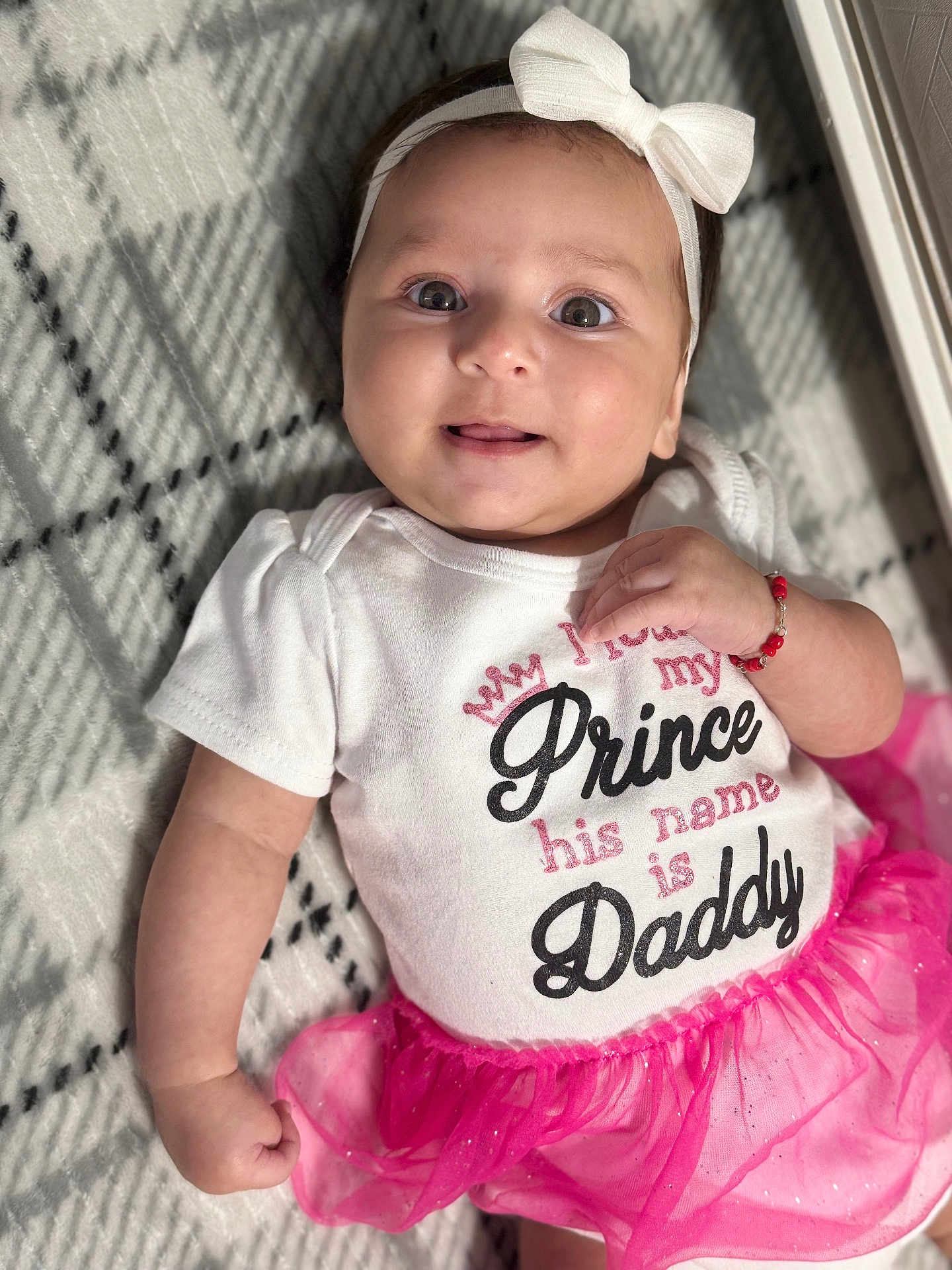 Valery is registered to the contest to win money with this photo: baby, infant, headband, bow, white_clothing, pink_tutu, smiling, face, arm, hand, blanket, patterned_blanket, cute, child, portrait, indoor, happy, young_child, person, fashion