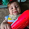 Aidan joined the competition — help win amazing prizes! baby, child, toy, carpet, colorful_clothing, bib, hand, smile, face, indoor, playtime, plastic_toy, striped_shirt, octopus_toy, closeup, person, infant, happy, floor, casual