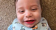 Aidan joined the competition — help win amazing prizes! baby, infant, smile, happy, carpet, bib, blue_clothing, cartoon_character, closeup, face, child, cute, young_child, indoors, person, playful, clothing, head, expression, toddler