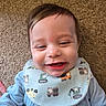baby, bib, blue_clothing, carpet, cartoon_character, child, closeup, clothing, cute, expression, face, happy, head, indoors, infant, person, playful, smile, toddler, young_child