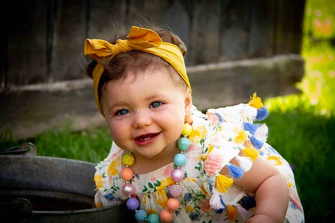 Remi is registered to the contest to win money with this photo: baby, baby_toddler_clothing, child, dress, event, eye, fashion_accessory, flash_photography, fun, grass, happy, head, headpiece, human_body, iris, joy, people_in_nature, person, plant, skin