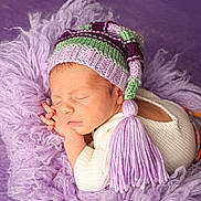 Tiago a rejoint le concours — aidez-le/la à gagner de superbes lots ! newborn, baby, sleeping, knit_hat, tassel, purple, blanket, soft_texture, cozy, infant, cute, portrait, resting, child, warm_clothing, closeup, peaceful, head, face, hands
