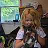 Princess is registered to the contest to win money with this photo: girl, child, kitten, cat, pet, gray_cat, white_paws, portrait, indoors, home, window, daylight, blonde_hair, long_hair, smiling, holding, animal, kitten_pose, blankets, furniture