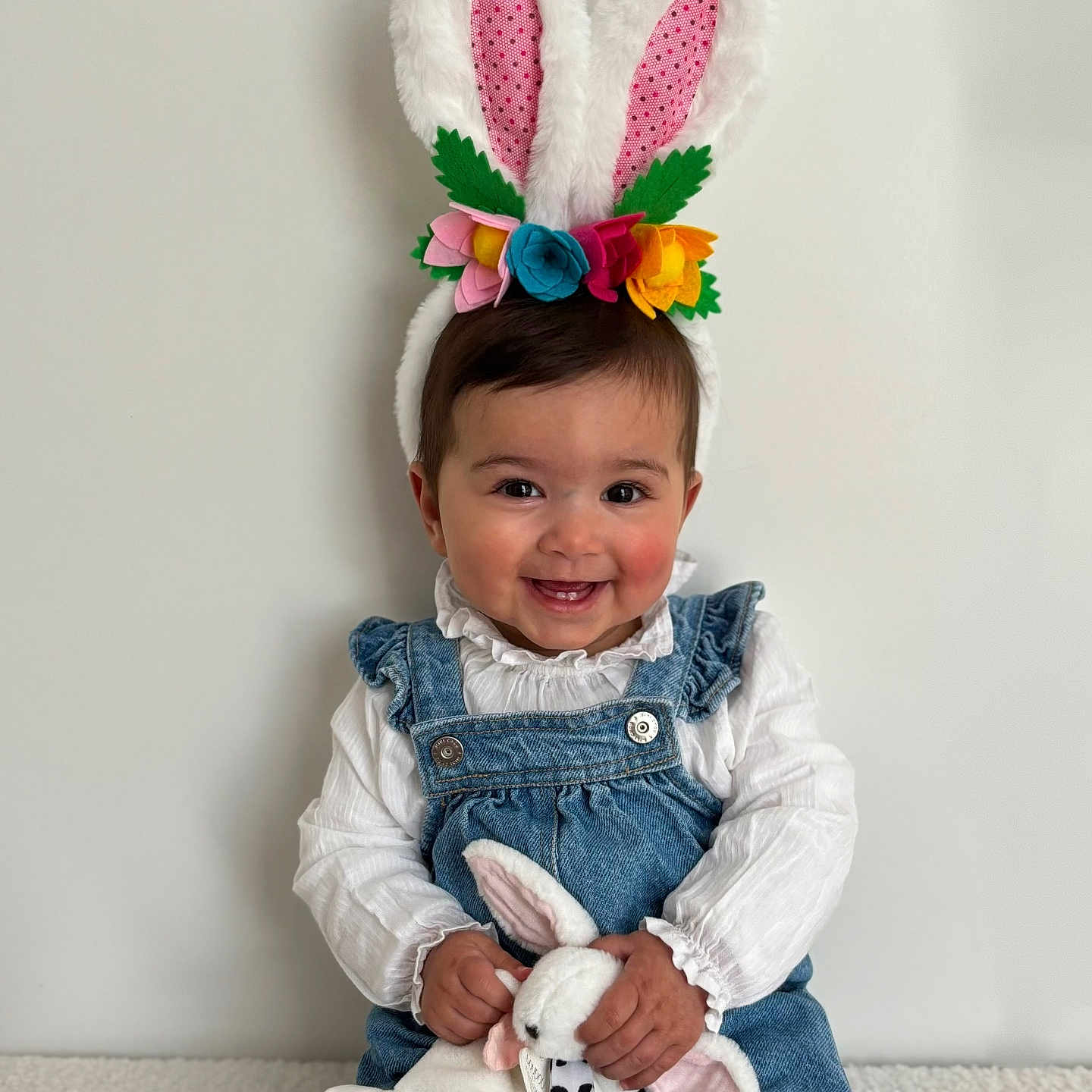 Giolia participe au concours pour gagner de l'argent avec cette photo : baby, bunny_ears, child, colorful_flowers, cute, denim_overalls, easter_theme, face, hands, happy, headband, indoor, plush_toy, portrait, sitting, smiling, soft_toy, toy, white_blouse, young_child