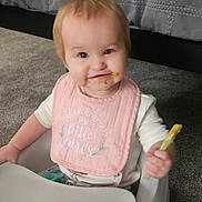 Skylar is registered to the contest to win money with this photo: baby, child, girl, smiling, bib, food, celery, baby_seat, carpet, bed, blanket, indoor, person, cute, happy, clothing, toddler, face, sitting, messy