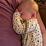 baby, child, infant, onesie, heart_pattern, pacifier, beads, hand, face, sleeping, cuddling, purple_shirt, person, closeup, skin, comfort, indoor, cozy, rest, parent