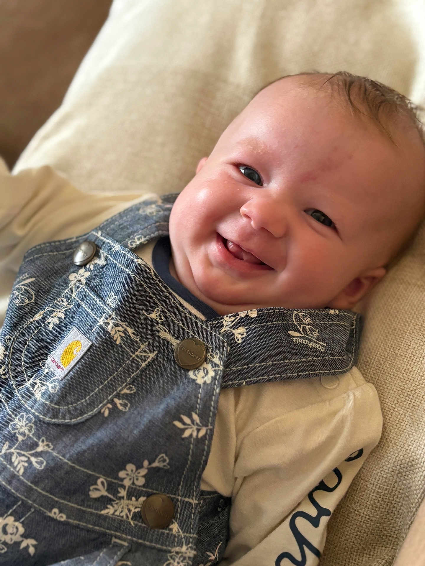 Blakely is registered to the contest to win money with this photo: baby, smiling, face, denim_overall, clothing, cushion, infant, happy, cute, portrait, child, young, indoor, fabric, button, person, skin, head, eyes, mouth