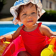 Leyana a rejoint le concours — aidez-le/la à gagner de superbes lots ! bright, child, colorful, cute, daytime, happy, inflatable_pool, outdoor, person, playing, pool, portrait, smiling, summer, sunhat, sunlight, swimsuit, toddler, toy, water