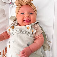 Elodie joined the competition — help win amazing prizes! baby, infant, smiling, tongue_out, headwrap, blue_eyes, buttoned_clothing, patterned_blanket, cute, happy, chubby_cheeks, lying_down, soft_fabric, child, adorable, young, playful, closeup, portrait, indoors