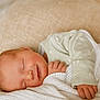 Elodie is registered to the contest to win money with this photo: newborn, baby, sleeping, smile, blanket, knitted_blanket, pillow, infant, soft_texture, closeup, peaceful, cozy, cute, child, resting, green_clothing, portrait, indoors, gentle, young