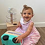 Ghevorchean Suzanna is registered to the contest to win money with this photo: baby, child, smiling, happy, pink_dress, striped_clothing, toy_car, wooden_floor, curly_hair, indoor, playtime, cute, infant, sitting, hand, foot, toy, background, person, closeup