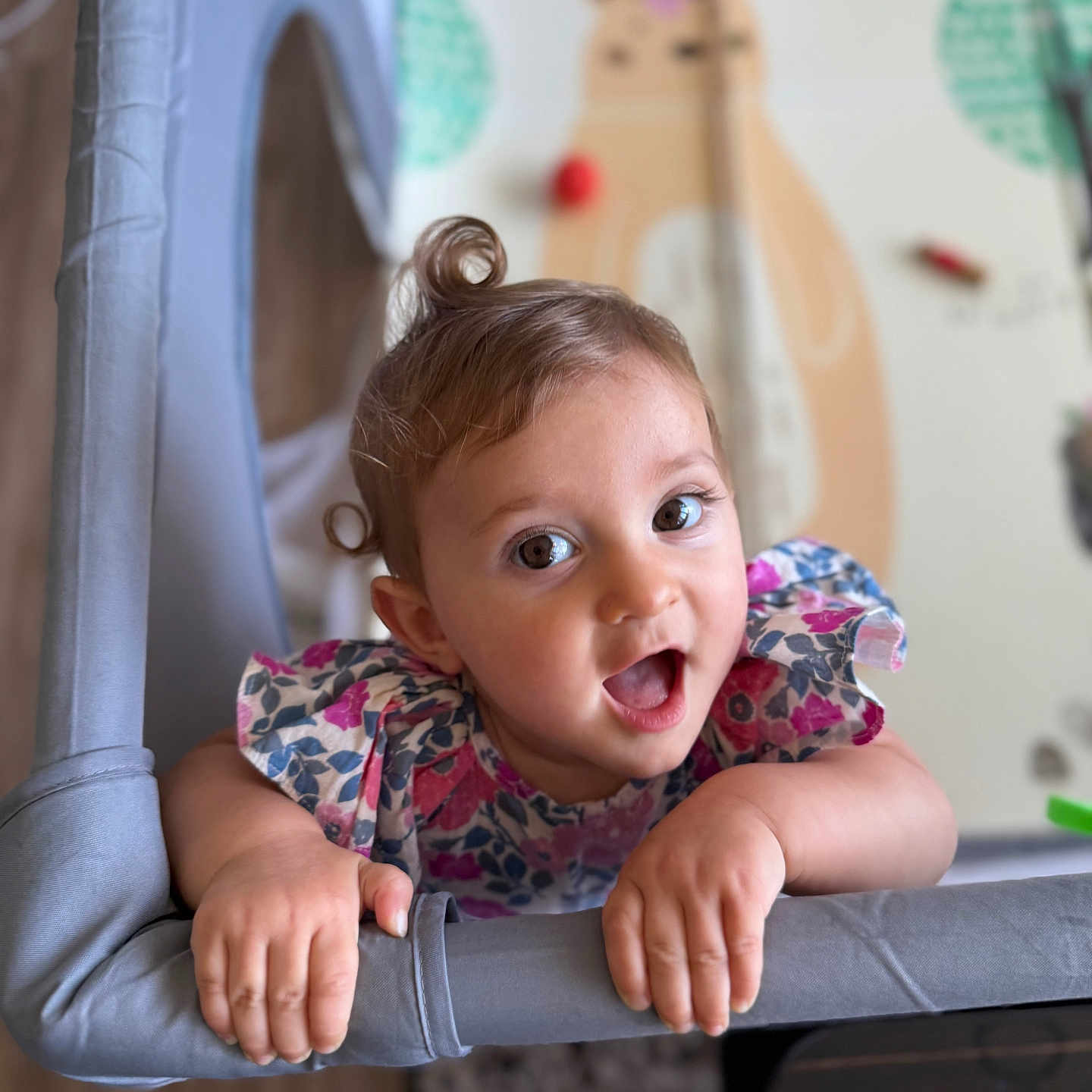 Ghevorchean Suzanna is registered to the contest to win money with this photo: baby, bright, child, colorful, curly_hair, cute, expression, face, floral_dress, grip, hand, happy, indoors, infant, nursery, person, playing, portrait, smiling, toy