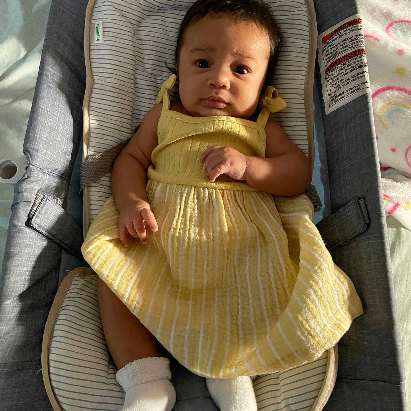 Cyenna is registered to the contest to win money with this photo: baby, child, yellow_dress, baby_seat, socks, indoor, portrait, infant, cute, childrens_clothing, striped_pattern, fabric, comfort, seat, small_hands, small_feet, looking, expression, soft_lighting, cozy