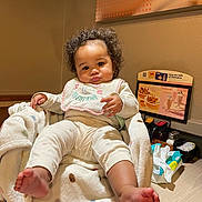 Cyenna joined the competition — help win amazing prizes! baby, child, curly_hair, blanket, bib, pajamas, foot, indoor, chair, table, menu, condiments, wall, room, cute, expression, person, infant, soft, cozy
