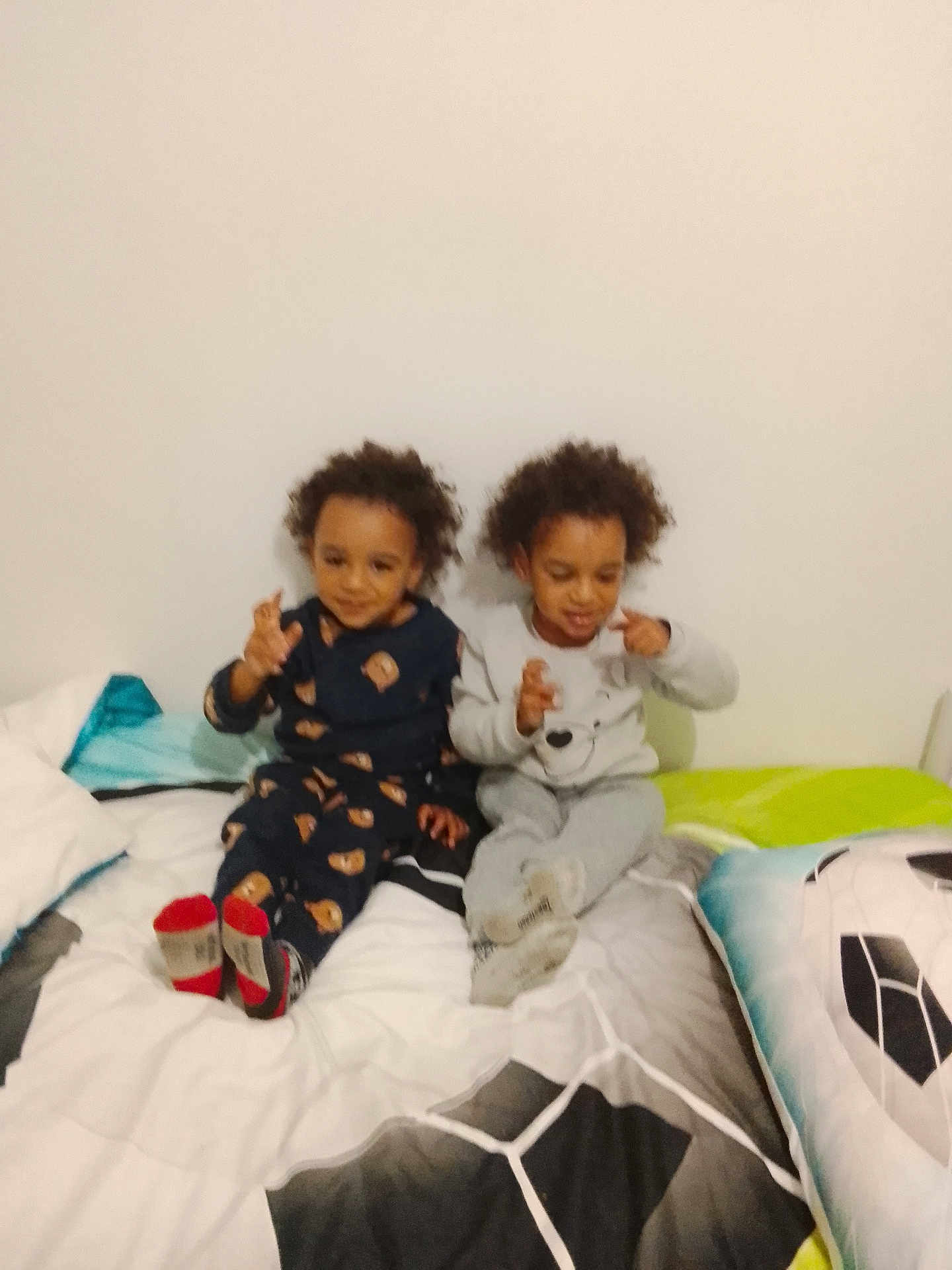 Khephren participe au concours pour gagner de l'argent avec cette photo : child, toddler, siblings, bed, blanket, pillow, pajamas, socks, smiling, curly_hair, bedroom, white_wall, playing, sitting, home, cozy, footwear, indoor, person, soccer_pillow