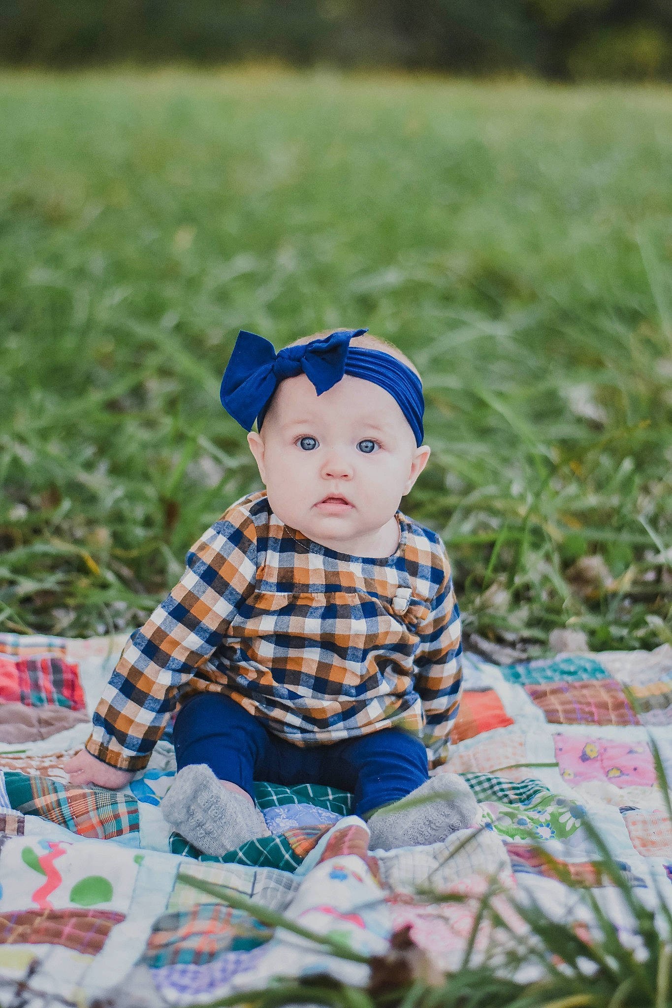 Nora is registered to the contest to win money with this photo: baby, baby_toddler_clothing, cap, child, doll, electric_blue, grass, grass_family, grassland, happy, hat, headwear, leaf, pattern, people_in_nature, person, plaid, plant, tartan, textile