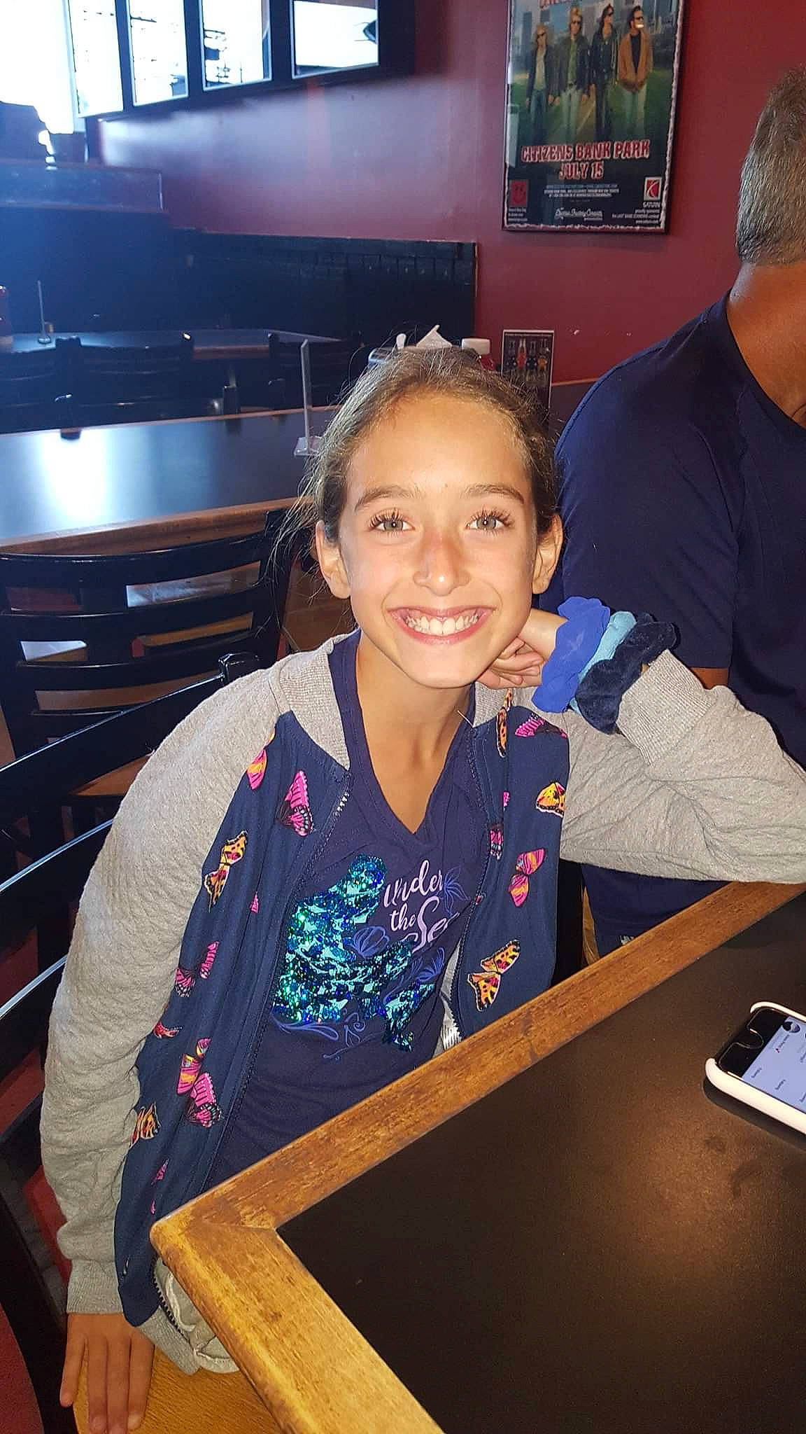 Madison is registered to the contest to win money with this photo: chair, communication_device, desk, event, fun, gadget, indoor_games_and_sports, job, joy, kitchen_appliance, leisure, mobile_phone, person, portable_communications_device, recreation, room, smile, t_shirt, table, tablet_computer