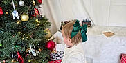 Emma joined the competition — help win amazing prizes! toddler, child, christmas_tree, ornament, holiday, decorations, green_bow, white_coat, barefoot, carpet, presents, red_ornament, indoor, curious, festive, celebration, holiday_decor, seasonal, young_child, exploring