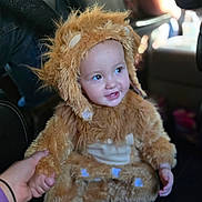 Emma joined the competition — help win amazing prizes! toddler, child, costume, lion_costume, furry, smiling, hand_holding, seat, car_interior, person, cute, baby, clothing, fur, seat_cover, portrait, happy, indoor, young_child, animal_costume