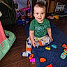 toddler, child, toy_blocks, rug, green_shirt, patterned_pants, indoor, floor, smiling, sitting, wooden_floor, furniture, playtime, colorful, person, happy, casual_clothing, home, young_child, toy