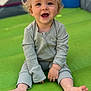 Carter is registered to the contest to win money with this photo: toddler, child, smiling, happy, blonde_hair, sitting, outdoor, playground, green_mat, barefoot, long_sleeves, casual_clothing, cute, portrait, young_child, sunlight, face, baby, one_person, infant