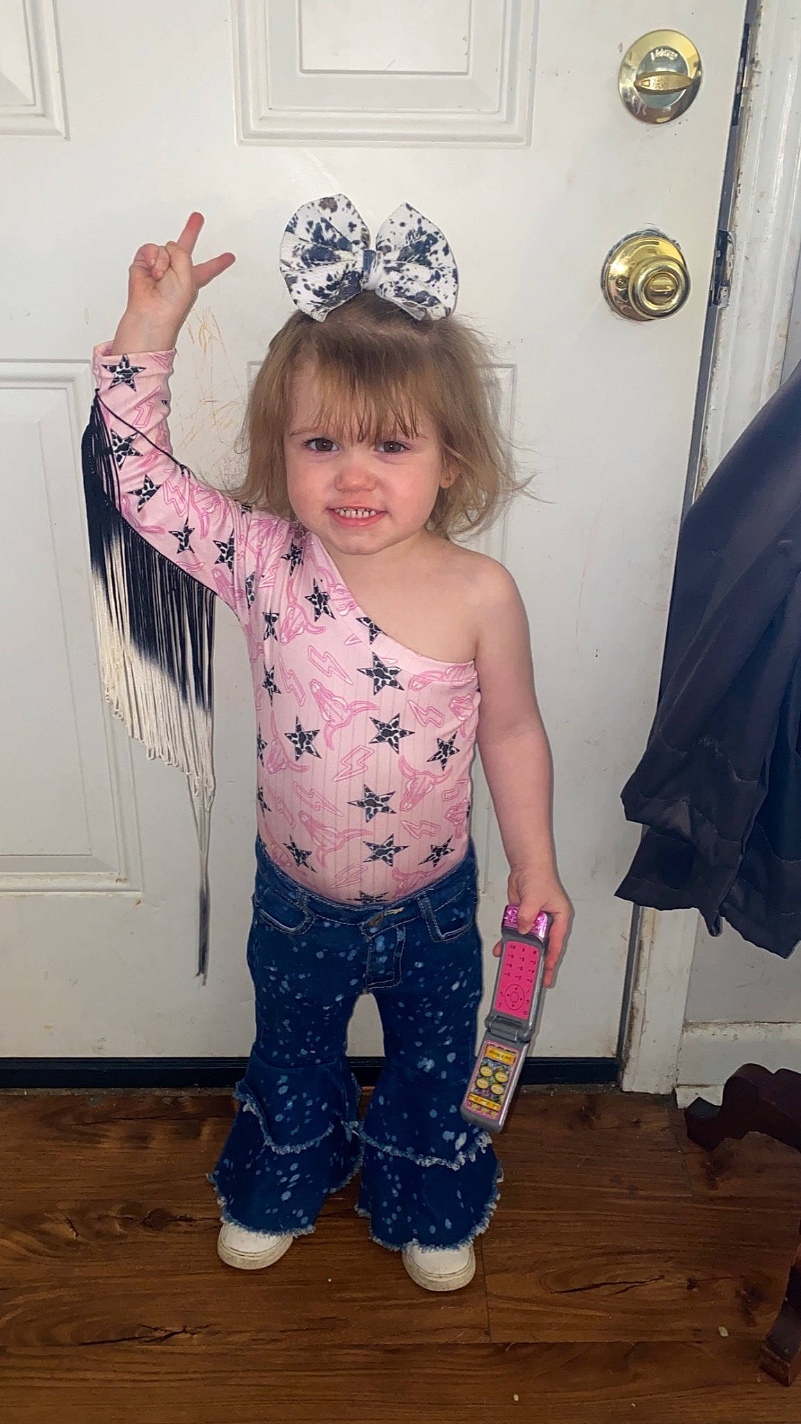 Oakleigh is registered to the contest to win money with this photo: baby_toddler_clothing, child, fashion_accessory, flooring, fun, gesture, hairstyle, happy, human_leg, joy, party_supply, pattern, person, picture_frame, pink, sleeve, smile, standing, textile, thigh