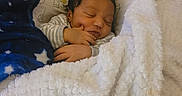 James is registered to the contest to win money with this photo: baby, newborn, sleeping, blanket, pillow, cozy, infant, child, soft, cute, resting, hand, face, bed, comfort, warmth, pattern, striped_clothing, peaceful, indoors