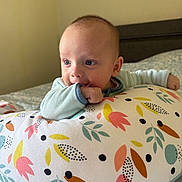 Mylan a rejoint le concours — aidez-le/la à gagner de superbes lots ! baby, infant, pillow, floral_pattern, indoor, curious, blue_eyes, chewing, sleeve, bed, blanket, soft_lighting, child, young, cute, resting, colorful, patterned, cozy, portrait