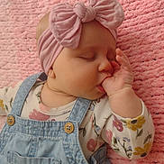 Harper joined the competition — help win amazing prizes! baby, infant, sleeping, thumb_sucking, headband, bow, denim_overalls, pink, blanket, soft_texture, cute, child, floral_shirt, peaceful, portrait, closeup, hand, face, indoors, cozy