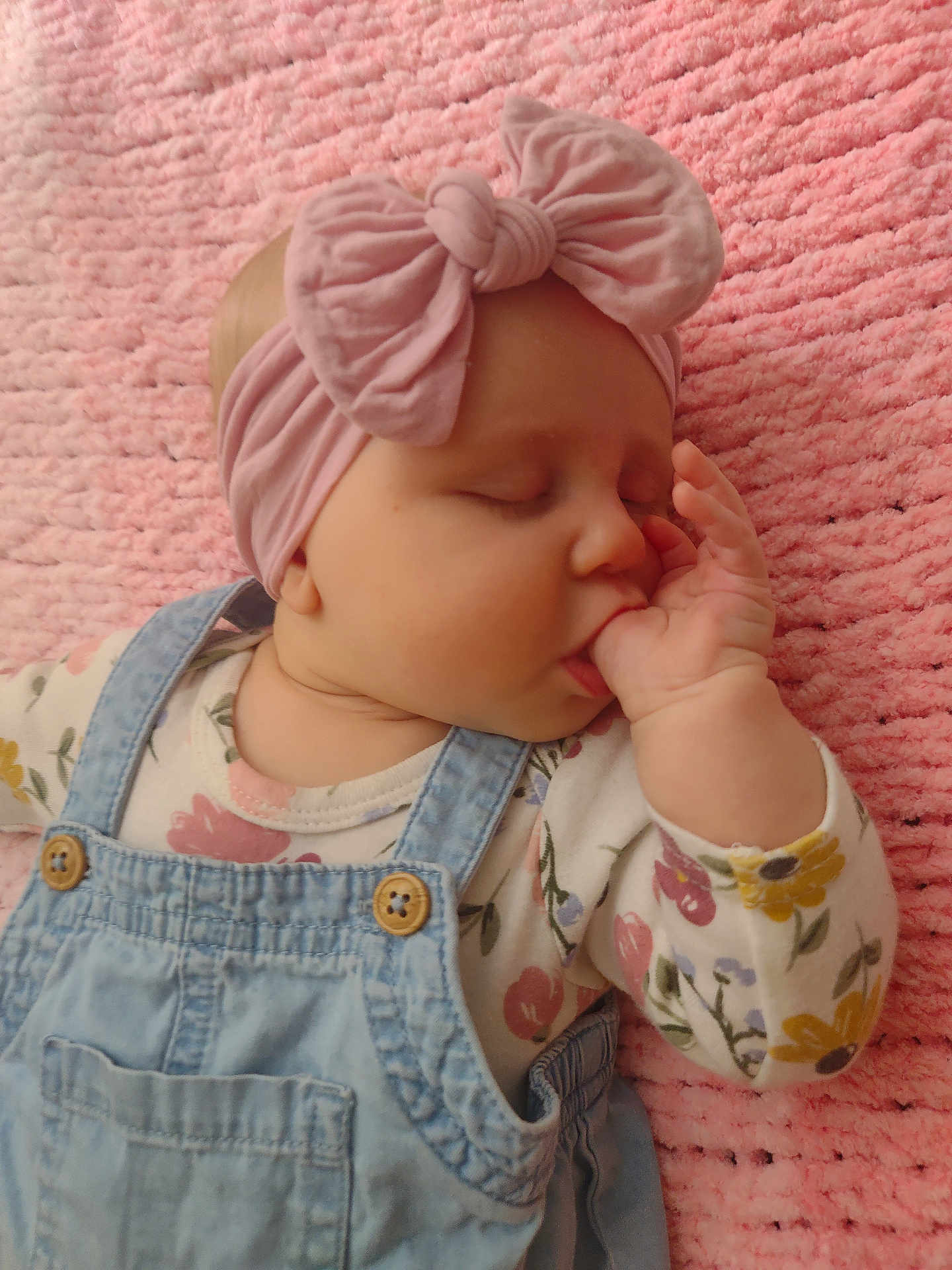 Harper joined the competition — help win amazing prizes! baby, infant, sleeping, thumb_sucking, headband, bow, denim_overalls, pink, blanket, soft_texture, cute, child, floral_shirt, peaceful, portrait, closeup, hand, face, indoors, cozy
