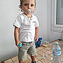 Francis a rejoint le concours — aidez-le/la à gagner de superbes lots ! toddler, child, pacifier, white_shirt, shorts, curly_hair, kitchen, table, water_bottle, glass, box, biscuits, shoes, window, indoor, person, standing, holding, food, drink