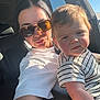 David is registered to the contest to win money with this photo: arm, baby, blue_sky, car, casual_clothing, child, daylight, face, family, head, indoor, person, portrait, seat, smile, striped_shirt, sunglasses, sunlight, window, woman