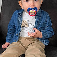 Ethan participe au concours pour gagner de l'argent avec cette photo : beige_pants, casual, child, clothing, couch, cute, denim_jacket, expression, face, furniture, hair, indoor, pacifier, person, portrait, sitting, small_object, toddler, white_shoes, young