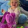 baby, child, smiling, toy, plush, blanket, colorful, easter_grass, purple, blue, yellow, green, plastic, indoor, happy, cute, face, person, play, carpet