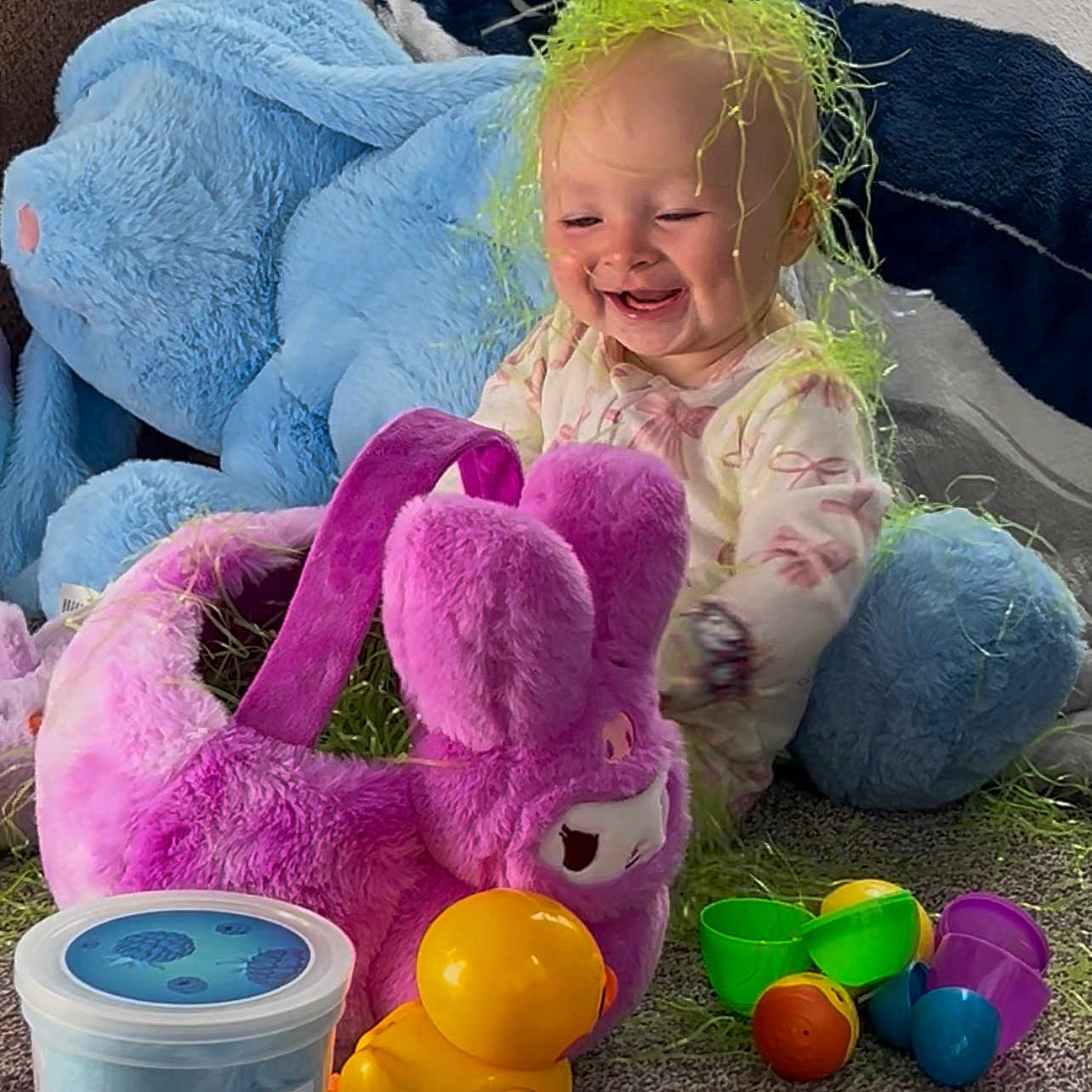 Haizley is registered to the contest to win money with this photo: baby, child, toys, plush_bunny, rubber_duck, colorful, floor, carpet, stuffed_animal, green_grass, smiling, indoors, playtime, happy, cute, purple, yellow, blue, clothing, person