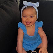 Ylona a rejoint le concours — aidez-le/la à gagner de superbes lots ! baby, child, blue_dress, headband, bow, smiling, sitting, couch, indoor, red_eye, happy, cute, infant, barefoot, hand, foot, skin, person, face, portrait