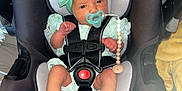 Huntleigh is registered to the contest to win money with this photo: baby, infant, car_seat, pacifier, headband, black, mint_green, clothing, newborn, sitting, safety_harness, indoors, floor, wood_floor, cute, person, child, infant_fashion, toddler, baby_accessory