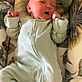 newborn, baby, infant, onesie, sleeping, cozy, cushion, floral_pattern, fabric, soft, cute, child, indoors, resting, peaceful, small_hands, lying_down, pink_socks, face, comfort