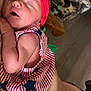 Huntleigh is registered to the contest to win money with this photo: baby, newborn, sleeping, headband, red, striped_clothing, stars, arm, hand, person, indoor, cushion, pattern, fabric, skin, face, peaceful, closeup, holding, comfort